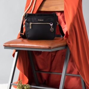 Black handbag on a chair with orange cloth, book, and decorative plant for a modern look.