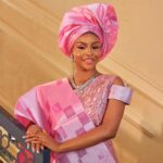 Stunning woman in vibrant pink traditional dress with intricate headdress, exuding cultural elegance and grace.